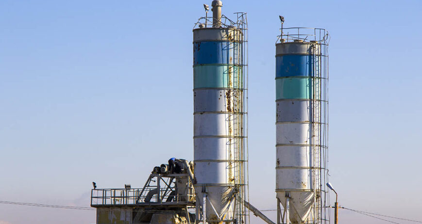 A view of the factory's high rusted reservoir tanks with stairs on blue sky background