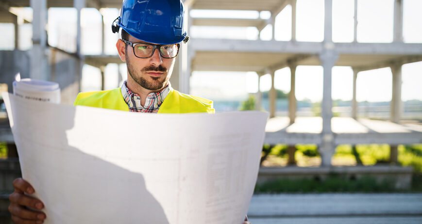 Construction engineer in hardhat with bluepront in hands