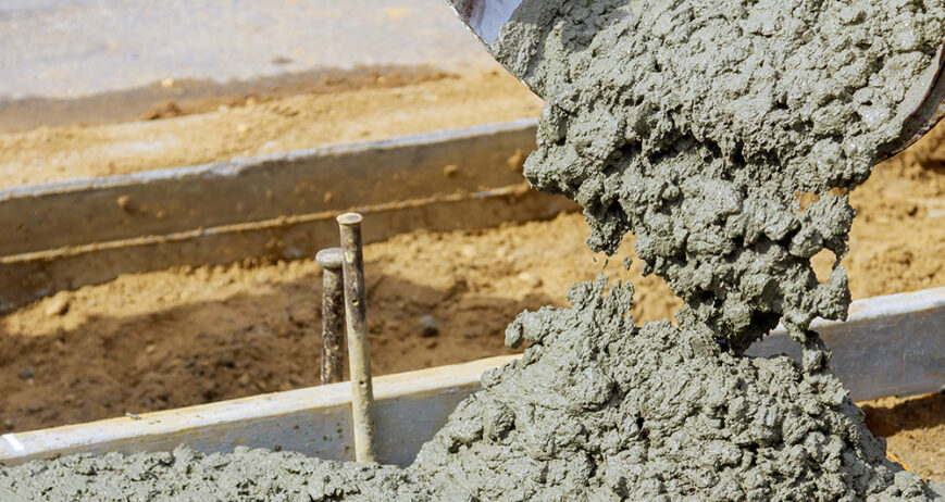 Concrete being poured from a mixer truck into a concrete with sidewalk