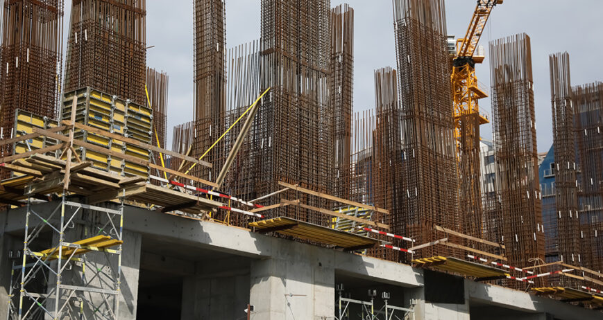 Tower crane near building under construction on sunny day
