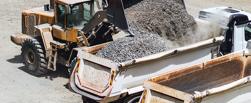 wheel loader working on construction site and loading gravel on dumper trucks. Heavy duty bulldozer working